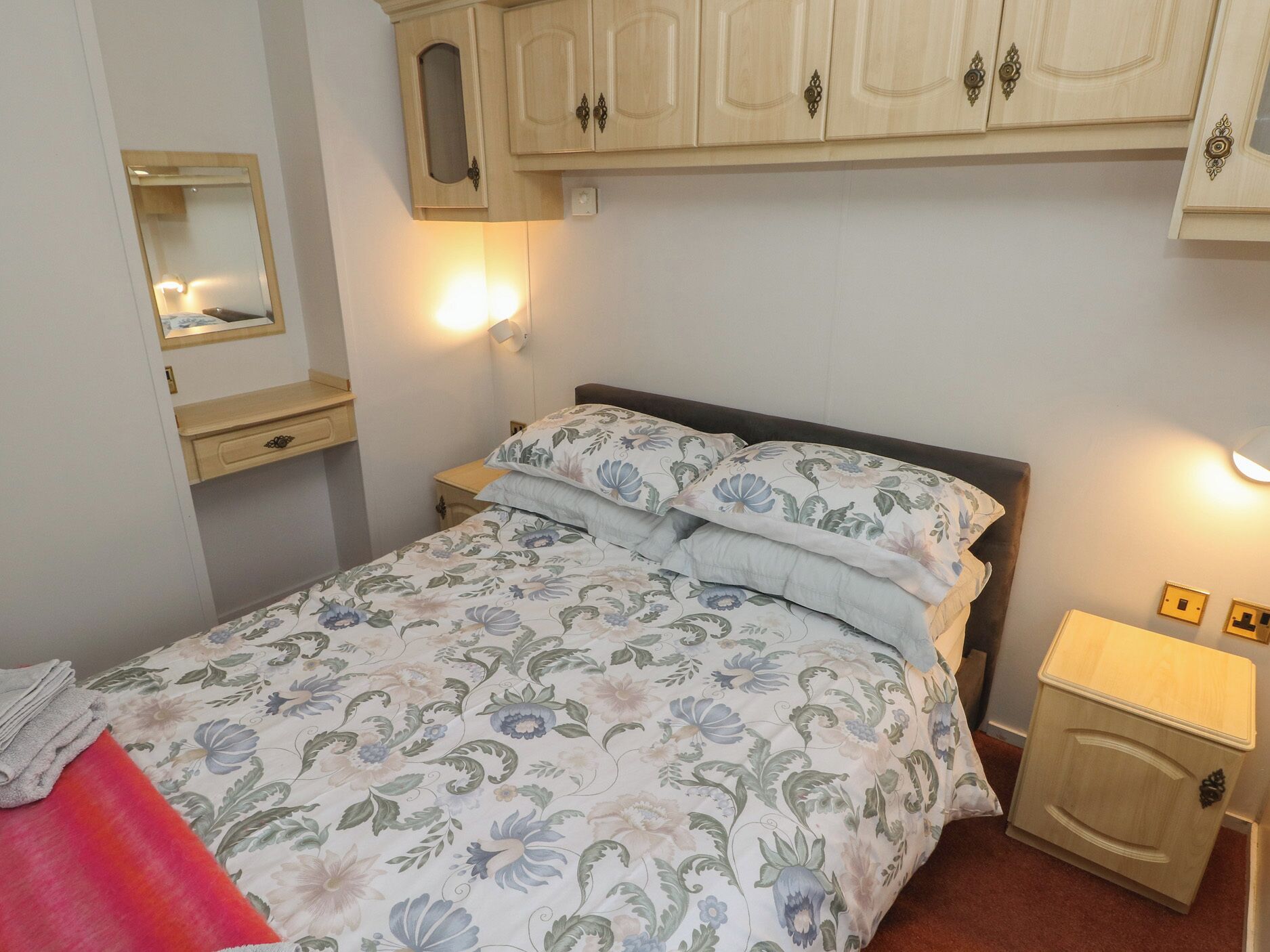 Ein Schlafzimmer mit Bett, Nachttisch, Schminktisch, Spiegel und Kleiderschrank.