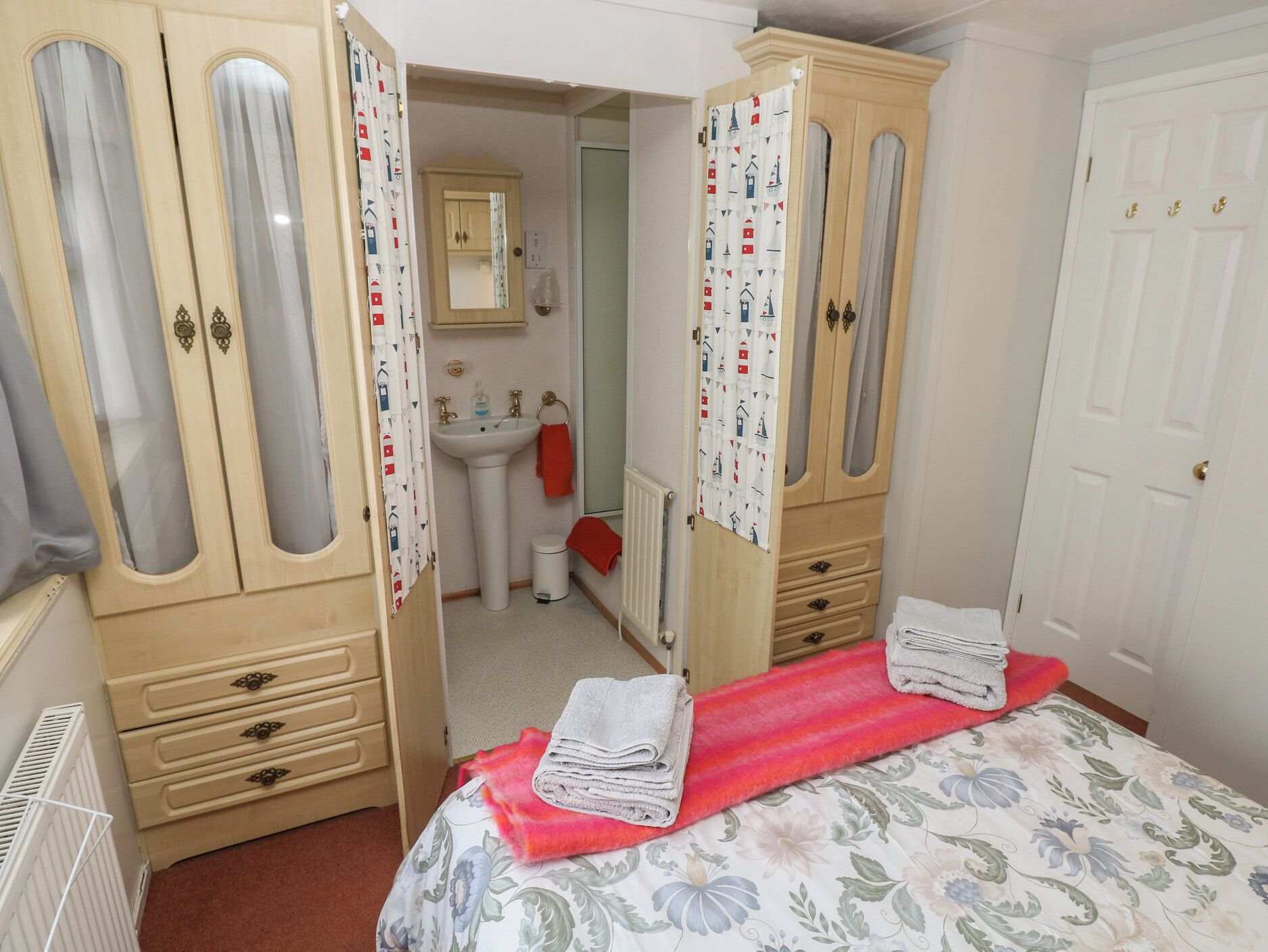 Ein Schlafzimmer mit einem Bett, einem Kleiderschrank, einem Spiegel, einem Waschbecken und einer Heizung.