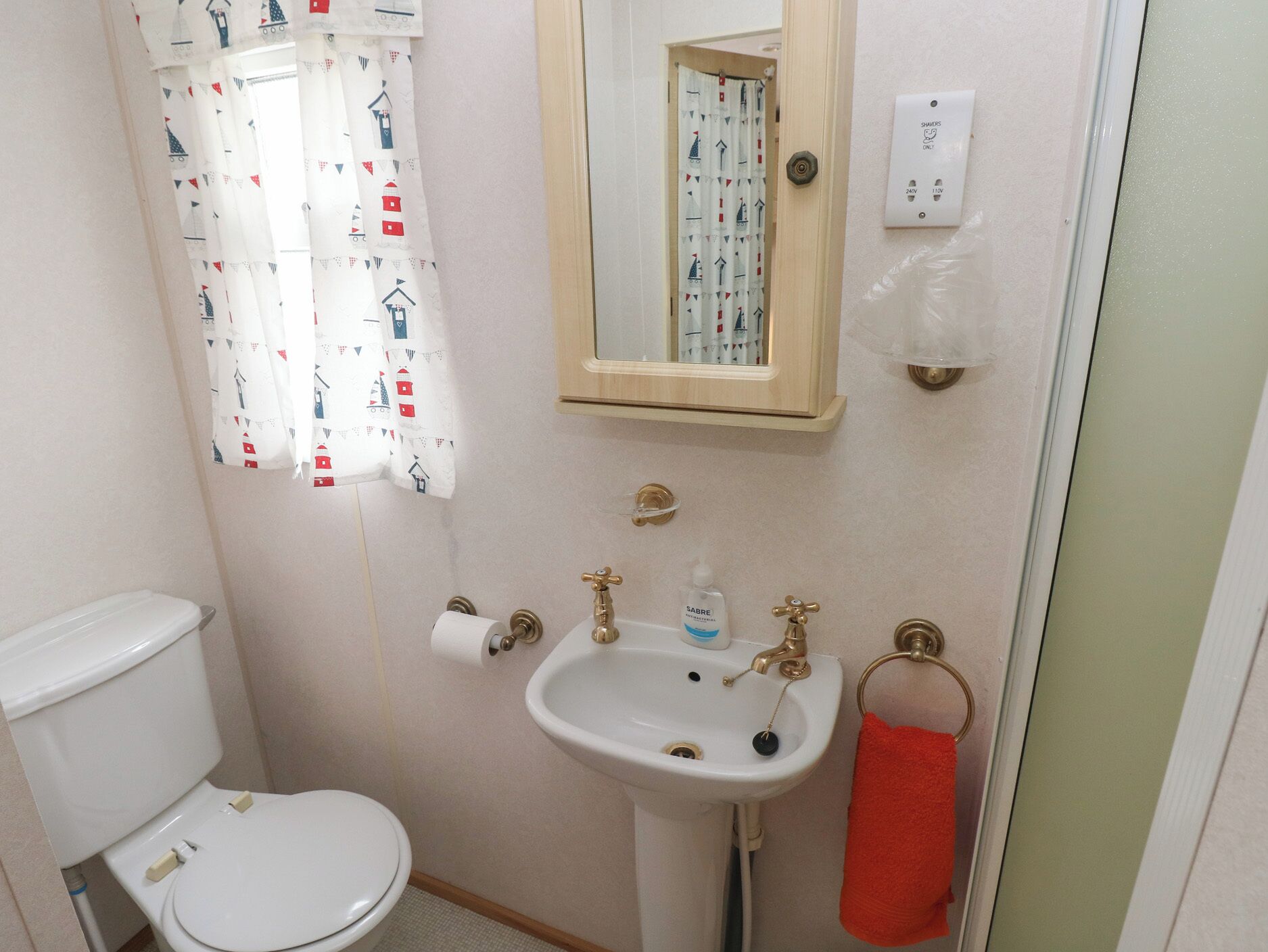 A small bathroom with a toilet, sink, and shower.