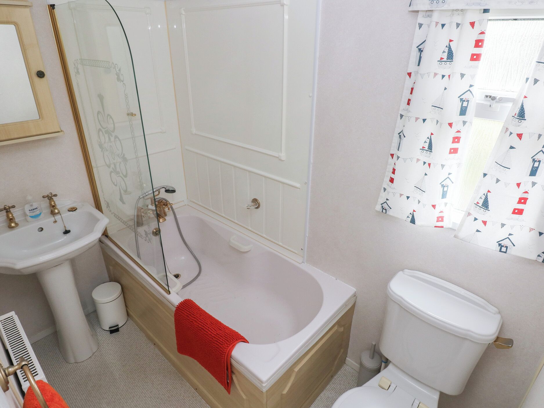 Un baño con bañera, inodoro, lavabo y ducha con puerta de vidrio.