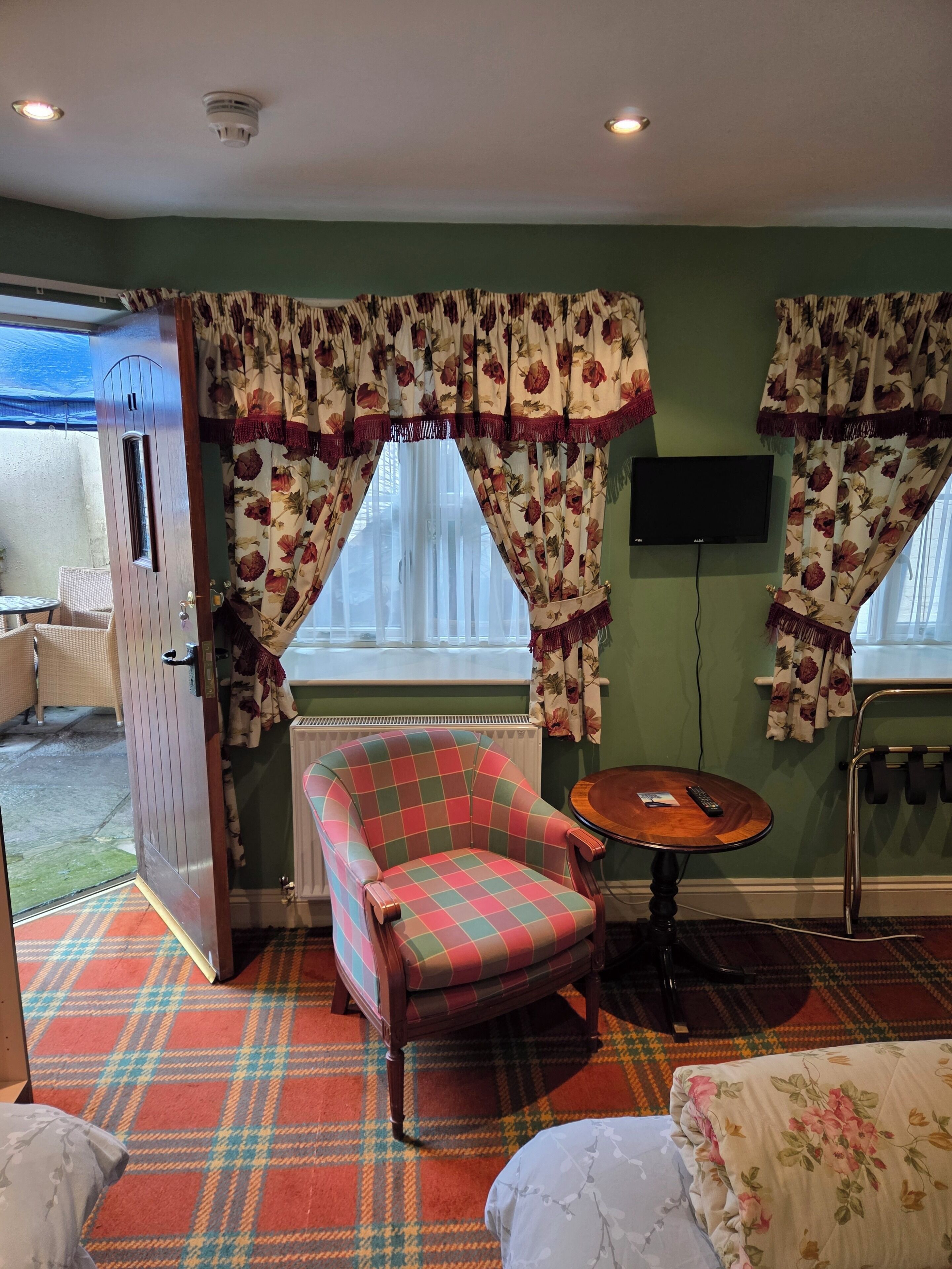 A cozy room with a plaid armchair, a small round table, and a television on the wall.