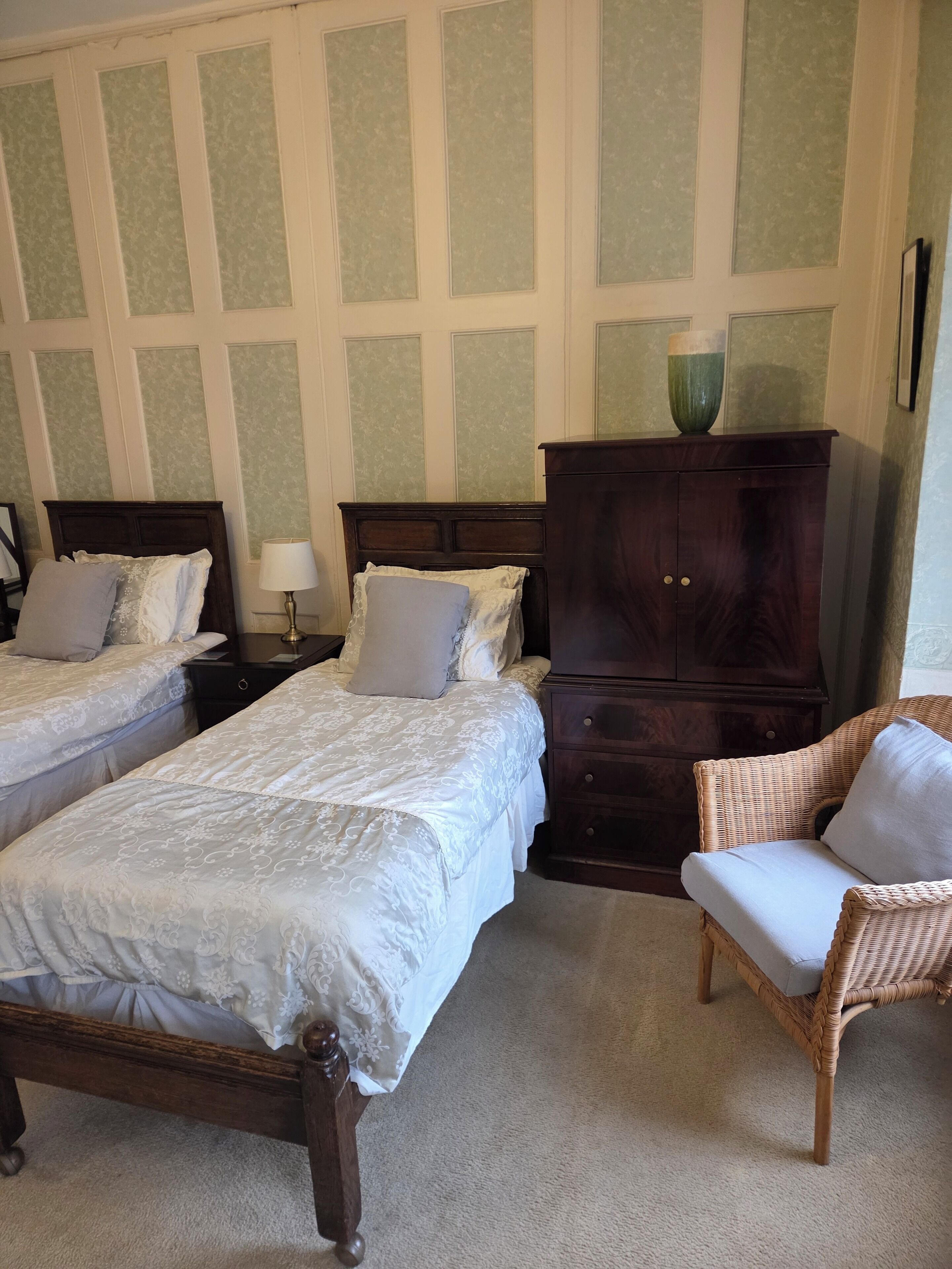 A bedroom with two beds, a dresser, a chair, and a lamp.