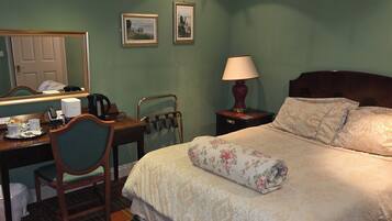 Une chambre d’hôtel avec un lit, un bureau, une chaise, une lampe et un miroir.