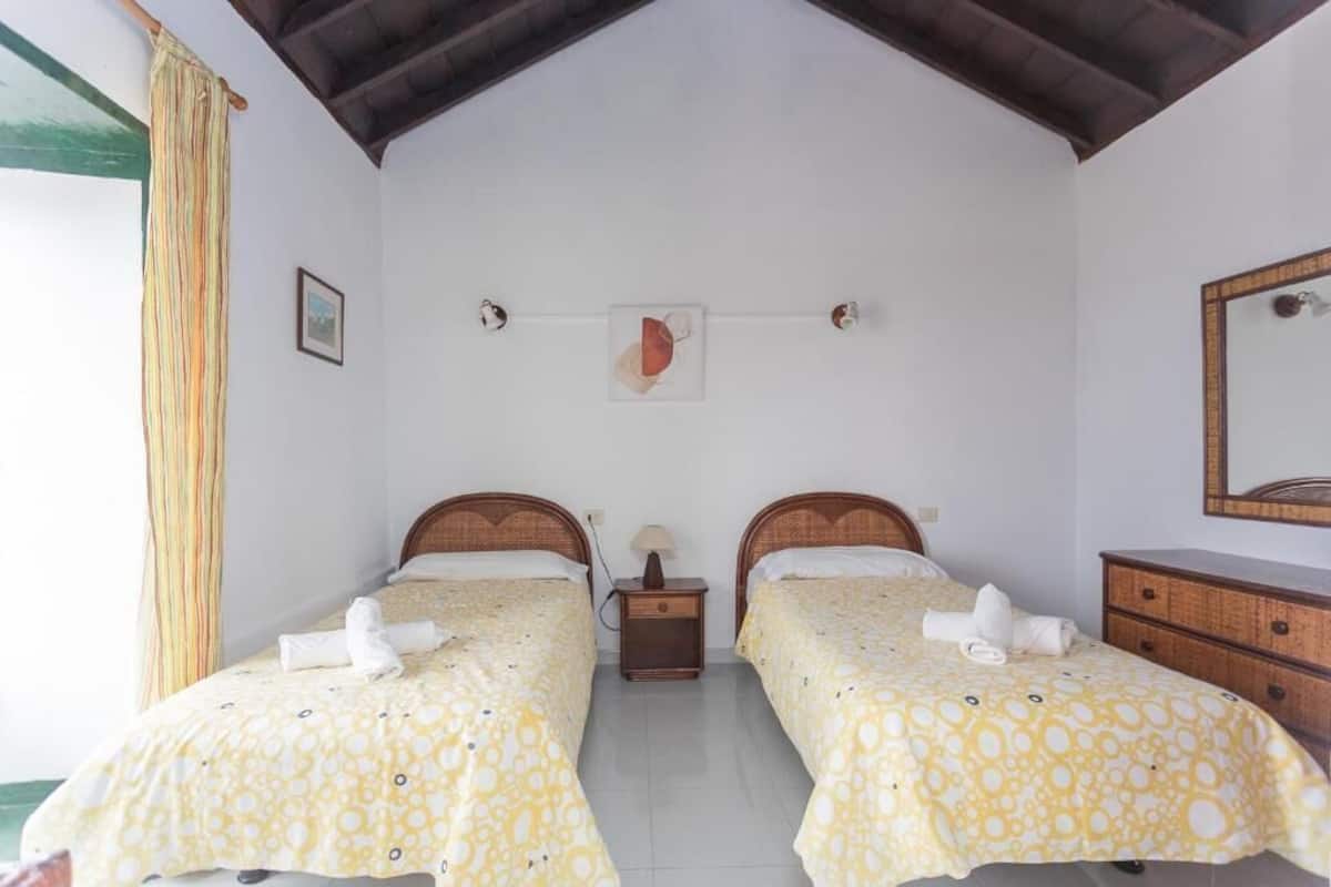 Una habitación con dos camas, un aparador de madera, una mesita de noche y un espejo.