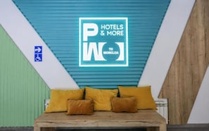 A hotel room with a bed, pillows, and a sign on the wall.