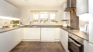 Une cuisine moderne avec des meubles blancs, un lave-vaisselle, une cuisinière et une fenêtre donnant sur l’extérieur.