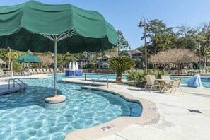 A swimming pool area with a green umbrella, lounge chairs, and a fountain. - Seven Night Stay in a 2 Bedroom Villa Near the Beach for Golf Tournament (Hilton Head Island)