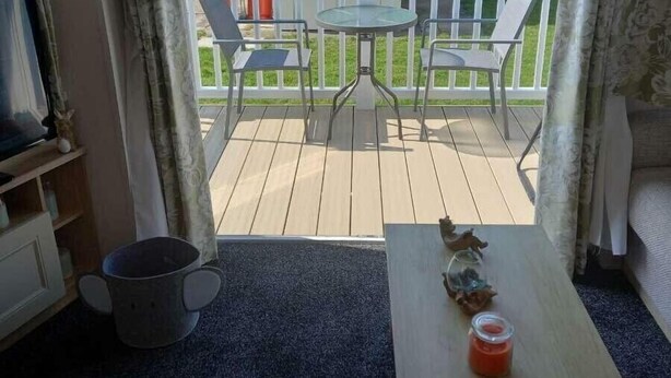 A room with a view of a backyard patio, a small table, and a chair. - Skegness Holiday Park 13968 (Skegness)