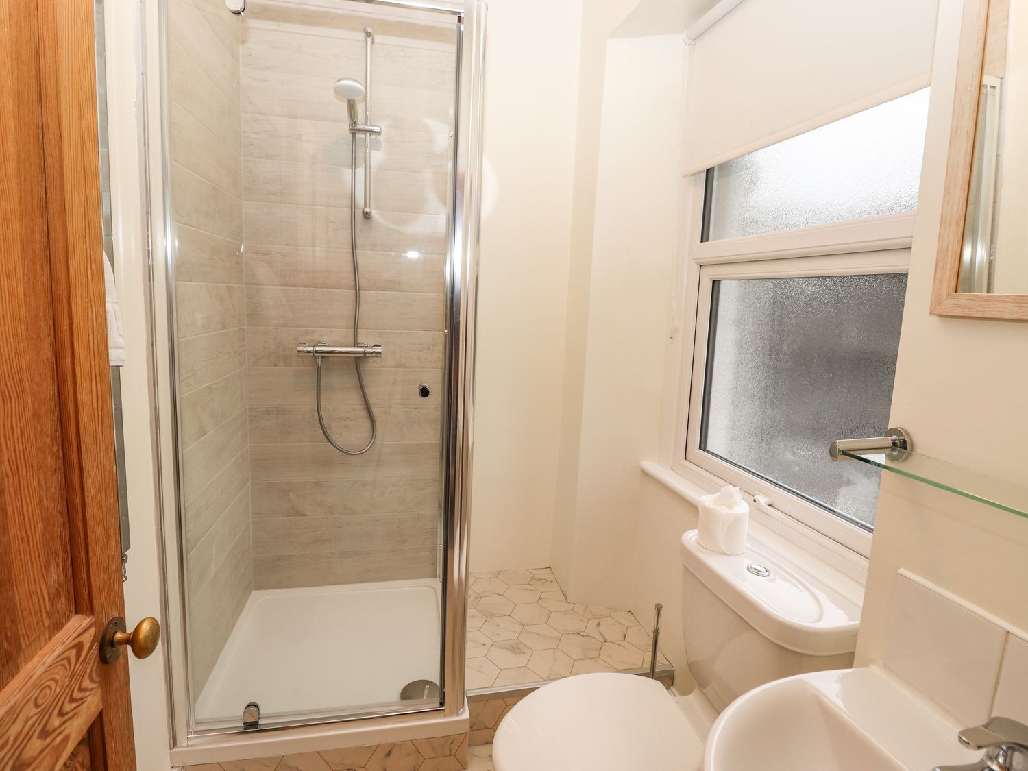 Un baño con ducha de vidrio, inodoro y lavamanos.