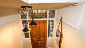 Un escalier surmonté d’une porte en bois, un radiateur et des toilettes blanches.