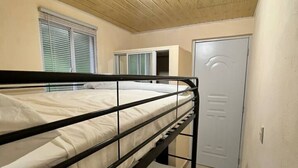 Dormitorio con literas, techo de madera y una ventana con persianas.