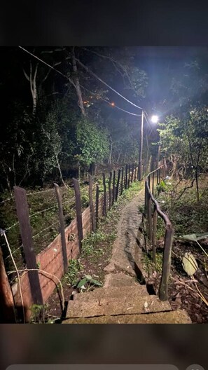A dimly lit wooden staircase surrounded by a wire fence, leading through a wooded area. - Family villa with private pool in jarabacoa (Jarabacoa)