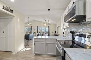 A modern kitchen with a large island, stainless steel appliances, and a view to the living area. - Stargazer! (Beech Mountain)
