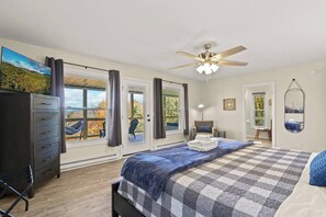 A bedroom with a large bed, a ceiling fan, and a view of the outdoors through the windows. - Stargazer! (Beech Mountain)
