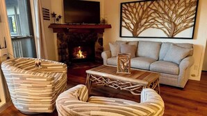 A living room with a fireplace, a sofa, and two striped armchairs. - Beech Please (Beech Mountain)