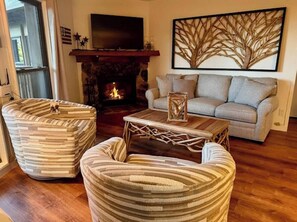 Ein Wohnzimmer mit Kamin, einer Couch und zwei gestreiften Sesseln.