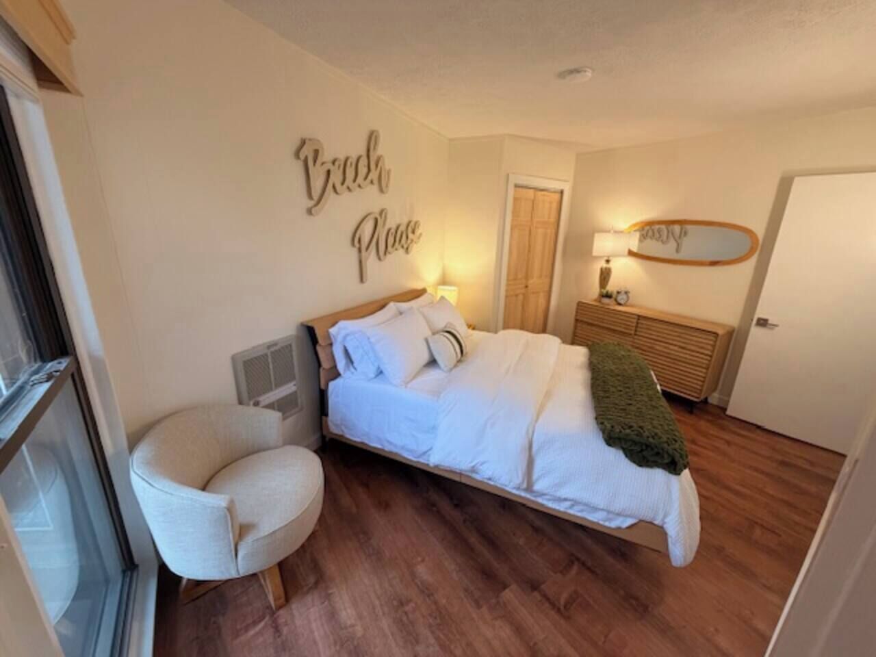 A bedroom with a bed, a chair, a bedside table, a lamp, and a wall with a 'Good Night' sign.