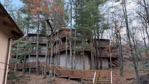 A multi-story wooden cabin with a wooden deck and stairs leading to the upper levels. - Beech Please (Beech Mountain)