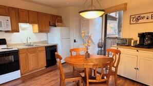 A kitchen with wooden cabinets, a dining table with chairs, a microwave, a refrigerator, and a coffee station. - Beech Please (Beech Mountain)