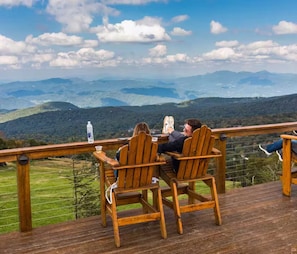 Zwei Personen sitzen an einem Holztisch mit Blick auf eine Berglandschaft.