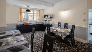 A dining area with a black and white patterned carpet, a black ceiling, and a window with curtains. - Lanayr Hotel Blackpool Limited (Blackpool)