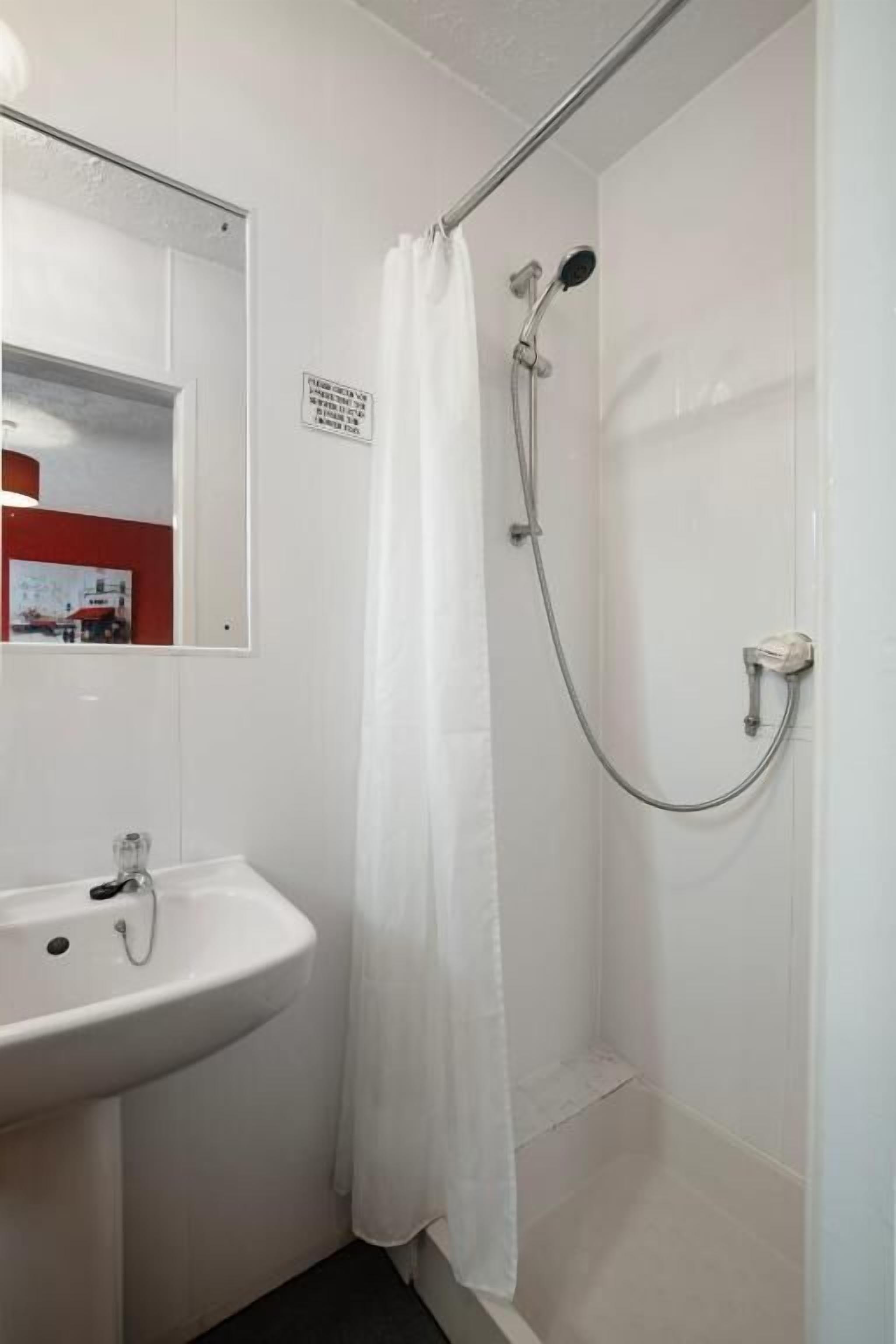 A bathroom with a white sink, a shower with a curtain, and a mirror.