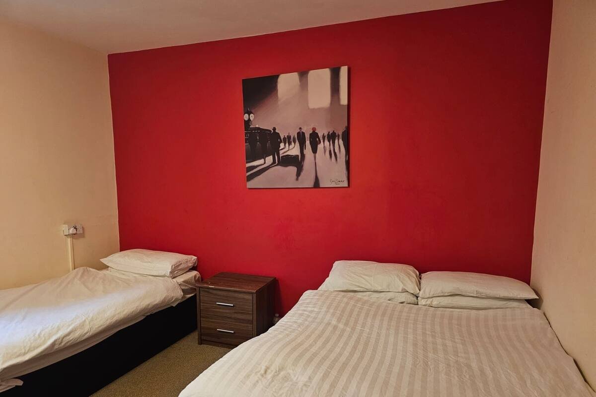 Ein Schlafzimmer mit zwei Einzelbetten, einer roten Wand und einem Stadtbild.