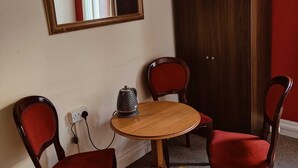 A room with a round wooden table, two red upholstered chairs, a dark wooden cabinet, and a mirror on the wall. - Lanayr Hotel Blackpool Limited (Blackpool)
