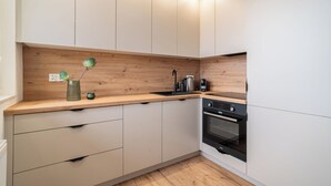 Una cocina moderna con encimeras de madera, armarios blancos y un horno empotrado.