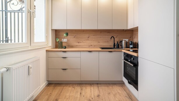 Una cocina moderna con armarios blancos, encimera de madera y electrodomésticos integrados.