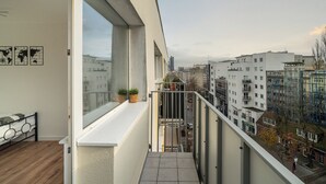 Un apartamento moderno con balcón, ventanas amplias y vista a la ciudad.