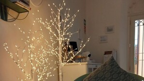 A room with a white artificial tree with lights, a teal chair, a bowl of candies, and papers on a table. - B&B Villino Luschi Pisa Centro (Pisa)