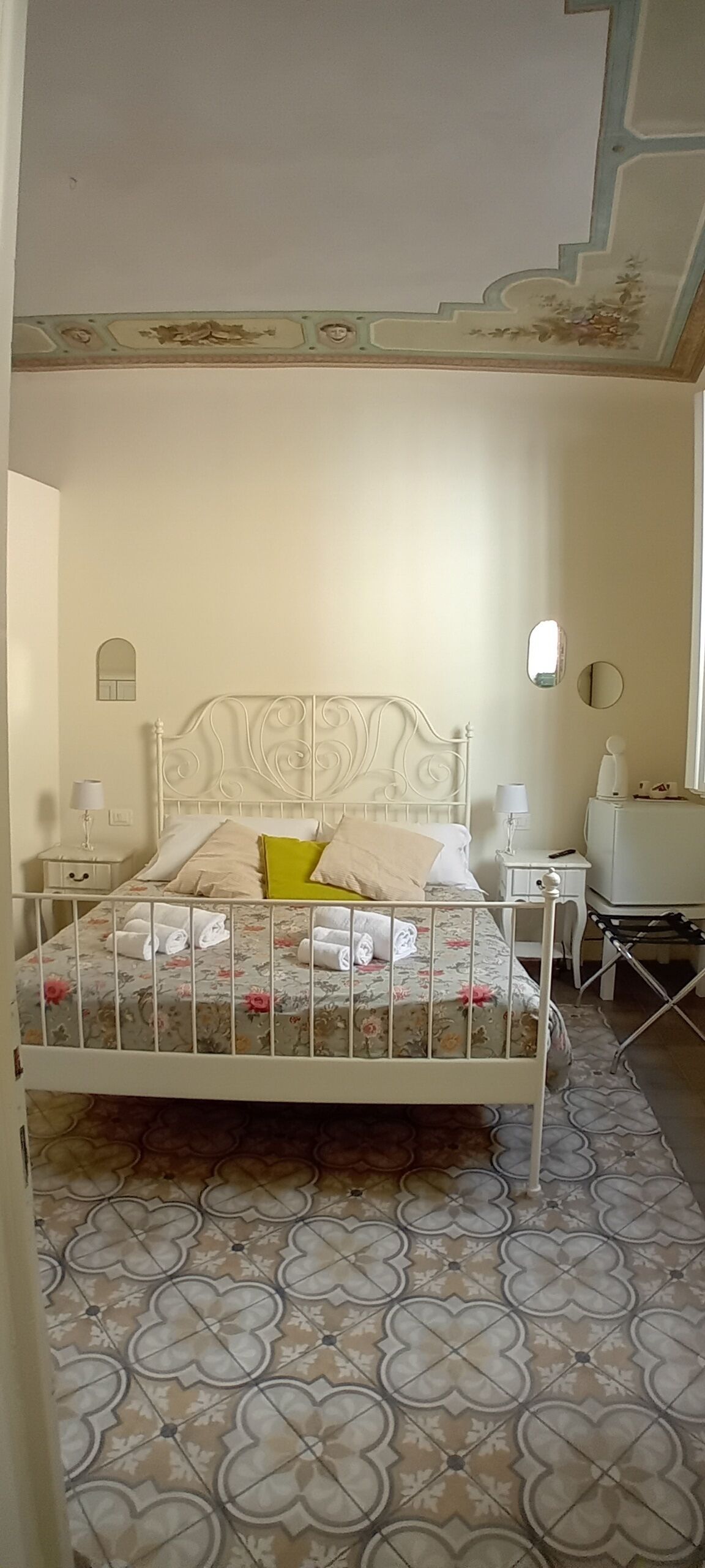 Een slaapkamer met een bed, nachtkastjes, een lamp, een spiegel en een klein bureau.