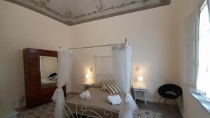 A bedroom with a four-poster bed, a bedside table with a lamp, a chair, and a wardrobe. - B&B Villino Luschi Pisa Centro (Pisa)