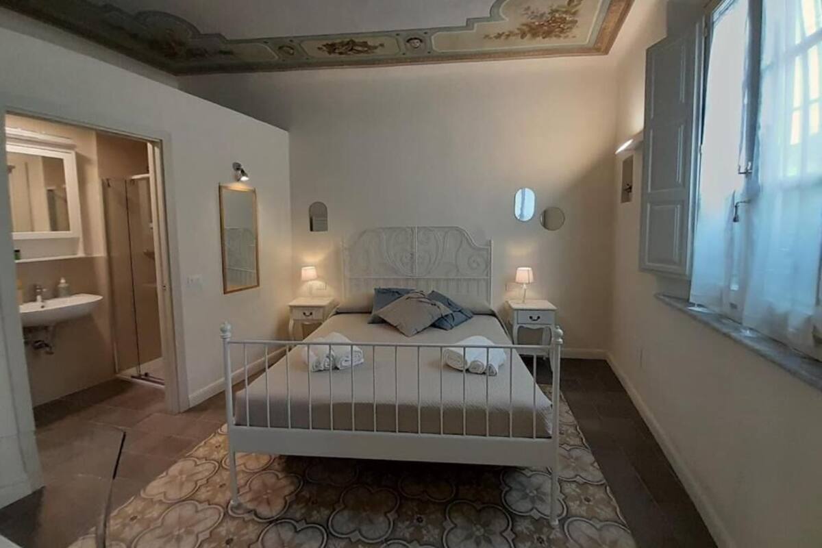 Ein Schlafzimmer mit Bett, Nachttischen, einem Spiegel und einem Fenster.