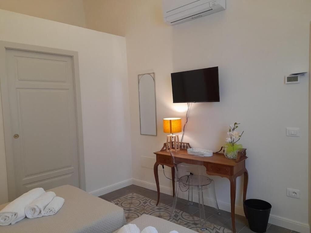 Ein Hotelzimmer mit Bett, Schreibtisch mit Lampe, Stuhl, Fernseher und Mülleimer.