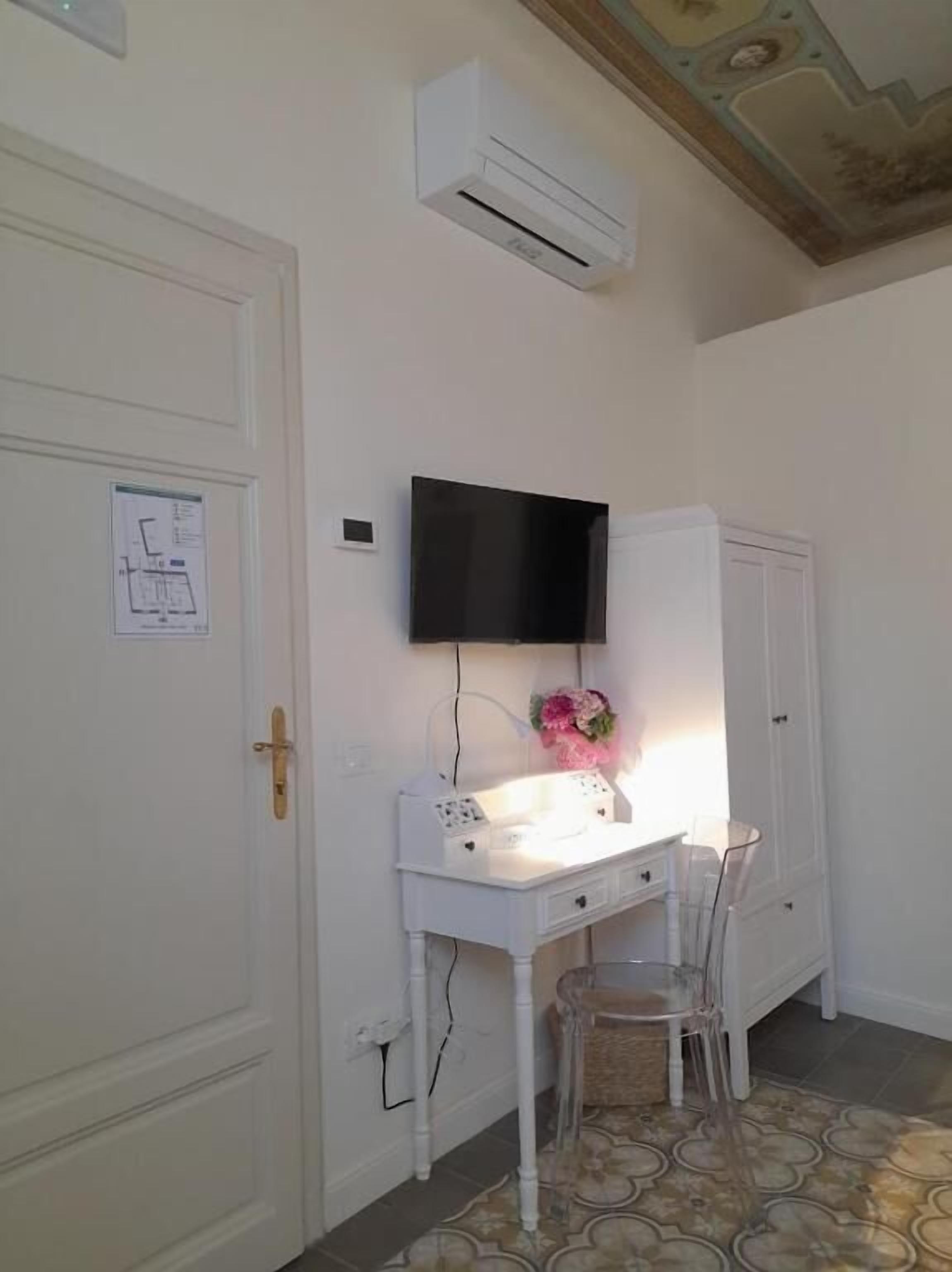 A room with a white desk, a mounted TV, and a chair.