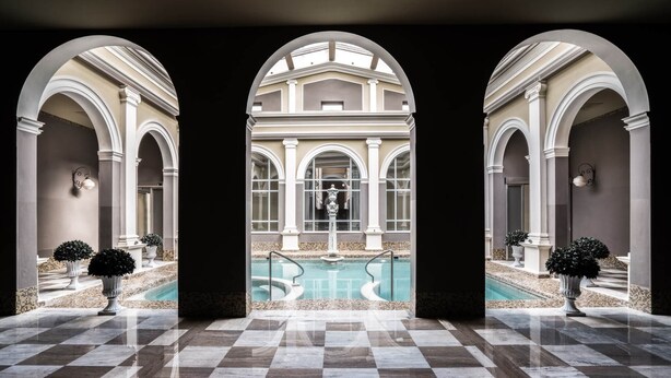 A luxurious pool area with a checkered floor, arched walkways, and a view of a building with classical architecture. - B&B Villino Luschi Pisa Centro (Pisa)