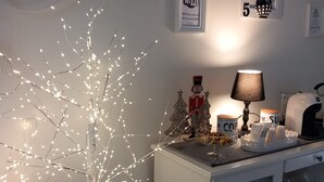 A room with a white cabinet, a small Christmas tree with lights, a lamp, and a wall-mounted sign indicating free Wi-Fi. - B&B Villino Luschi Pisa Centro (Pisa)
