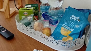 A tray with snacks, drinks, and a remote control on a wooden table.