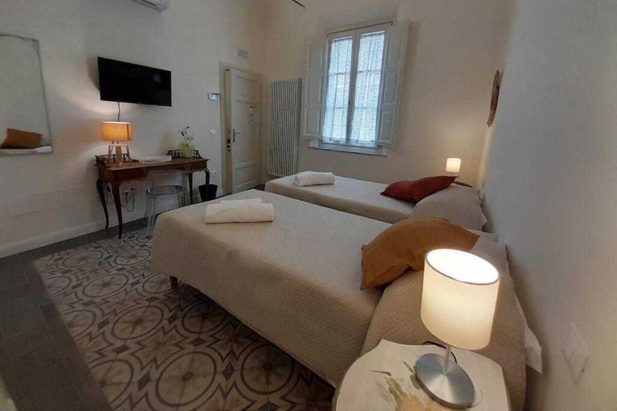 Ein Hotelzimmer mit zwei Betten, einem Schreibtisch, einem Stuhl, einem Fernseher und einem Fenster.