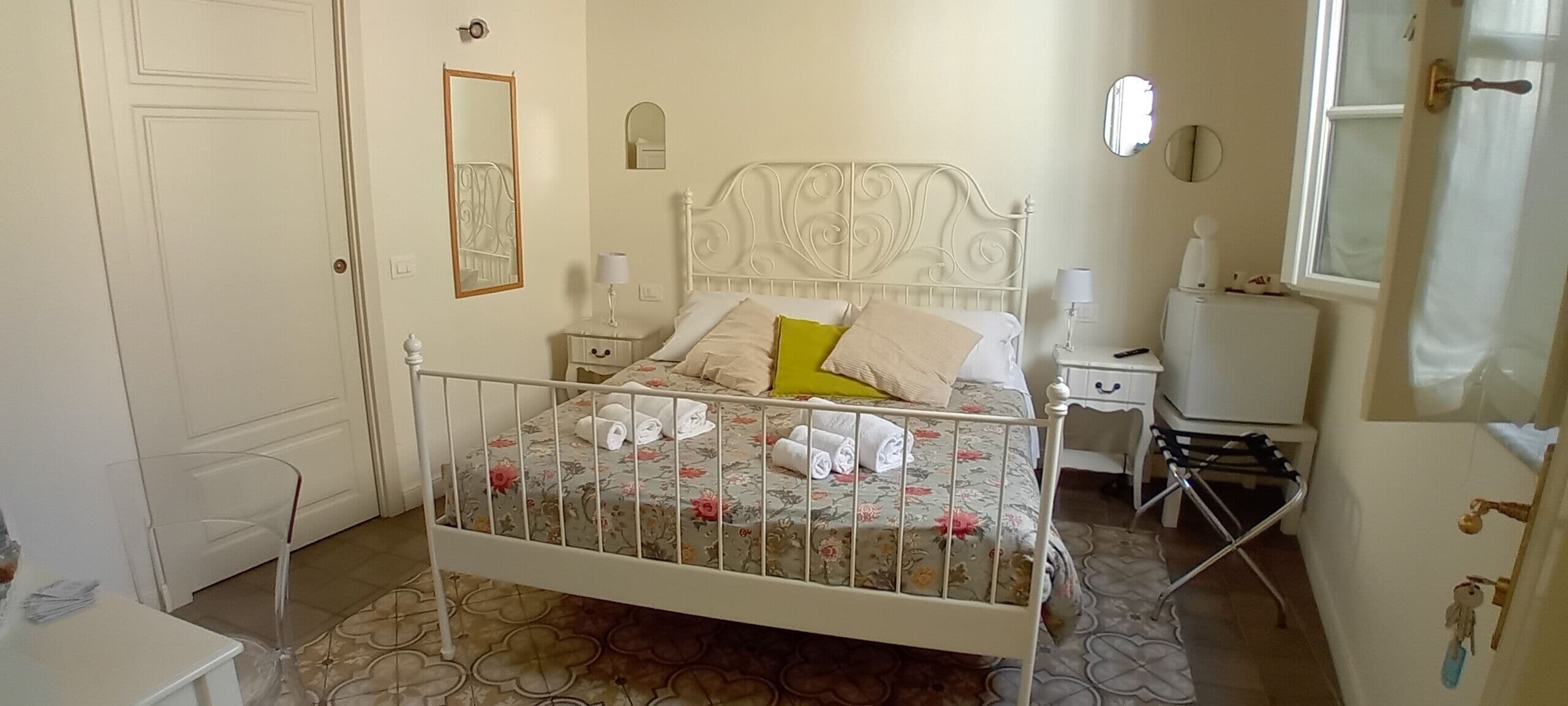 A bedroom with a bed, bedside tables, a mirror, and a window.