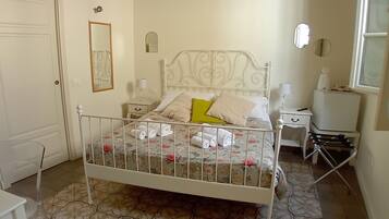 A bedroom with a bed, bedside tables, a mirror, and a window.