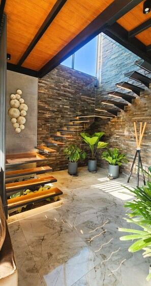 A modern interior with a wooden ceiling, a stone wall, and a staircase with built-in planters. - Casa La Parra by Wynwood House (Salas)