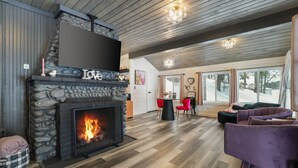 Un soggiorno accogliente con camino in pietra, soffitto in legno e ampie finestre.