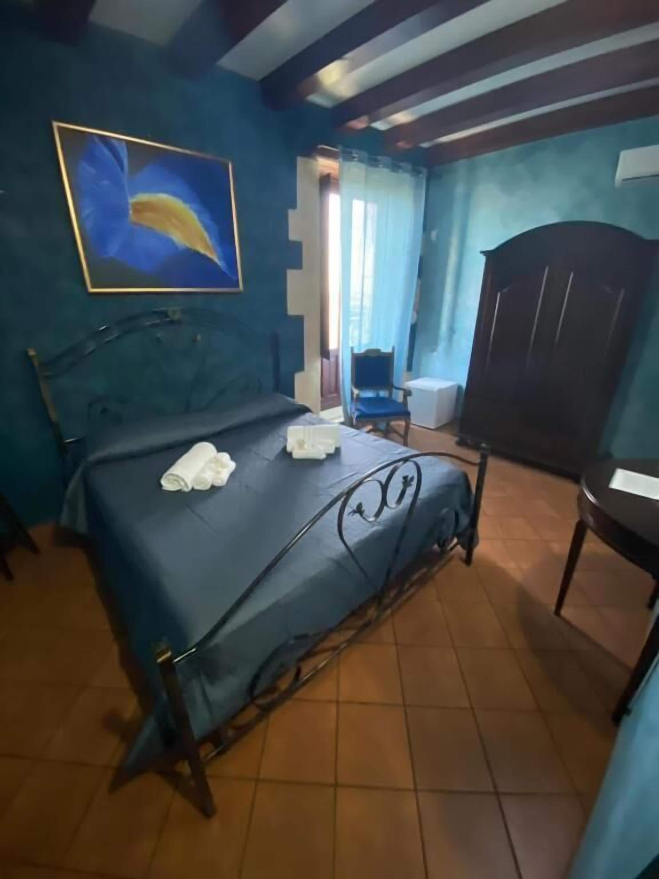 A bedroom with a bed, a chair, a wardrobe, and a painting on the wall.