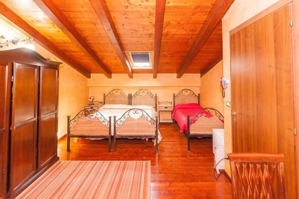 A bedroom with two beds, wooden ceiling beams, a skylight, and a wooden wardrobe.