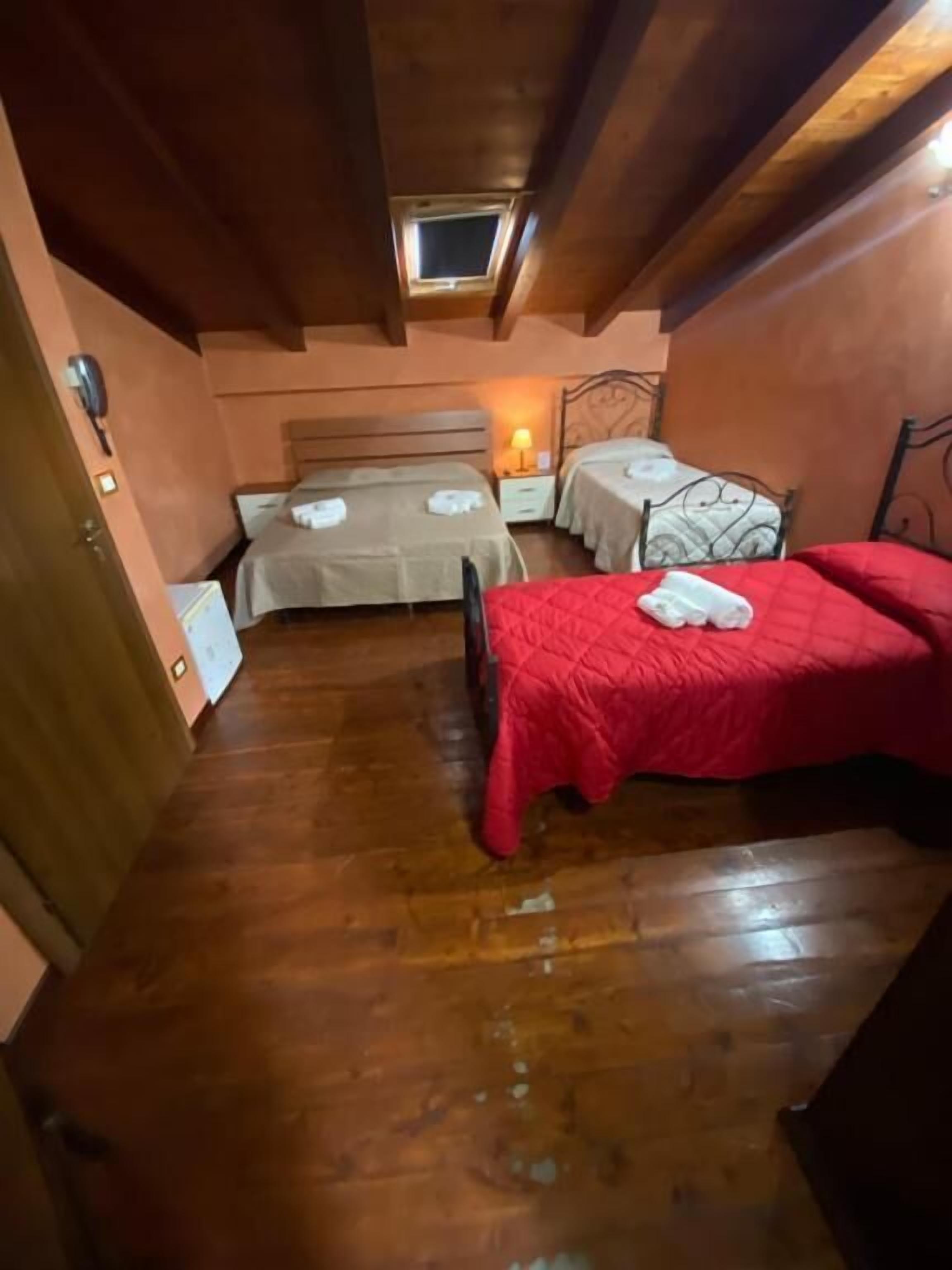 A cozy attic bedroom with two beds, wooden floors, and a skylight.