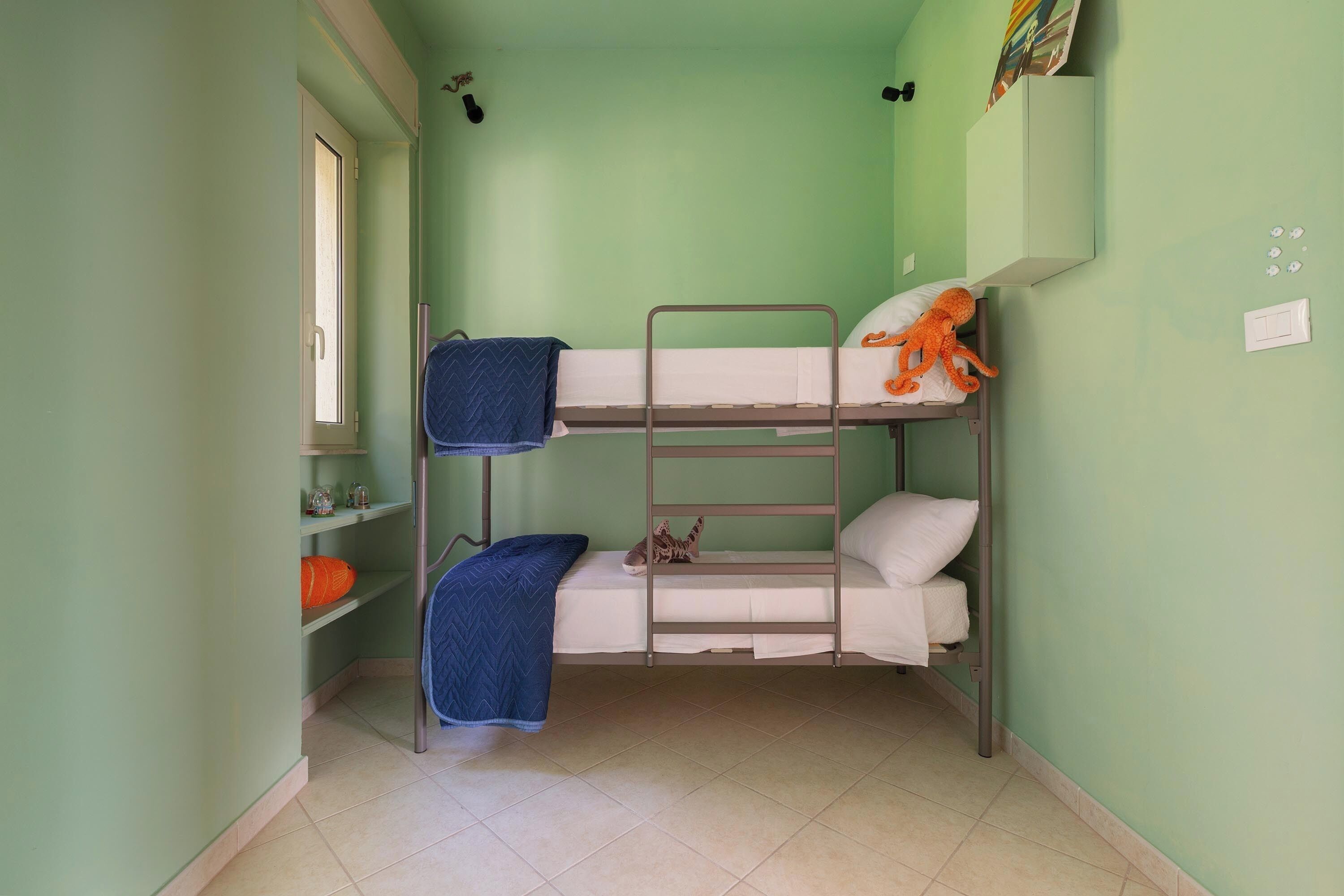 Ein Schlafzimmer mit Etagenbett, Fenster, Regalen und einer Tür.