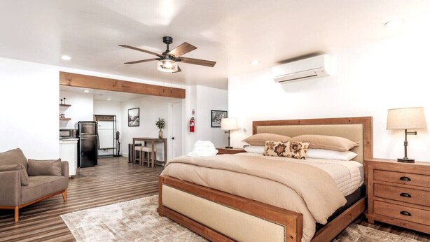 A bedroom with a wooden bed, a ceiling fan, a nightstand, and a bedside table. - Chic Yosemite Escape: King Suite w/ Plush Comforts (Oakhurst)